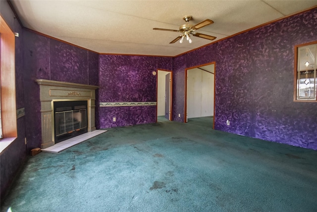 unfurnished living room with ceiling fan, a glass covered fireplace, carpet flooring, and ornamental molding