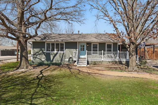 ranch-style home with a front lawn, fence, covered porch, and a shingled roof