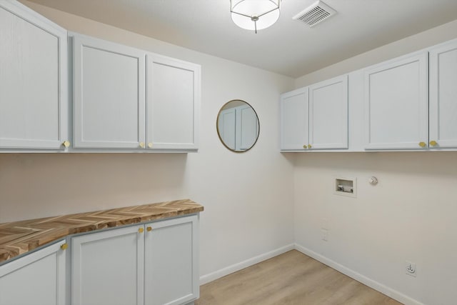 laundry room featuring hookup for a washing machine, visible vents, light wood finished floors, baseboards, and cabinet space