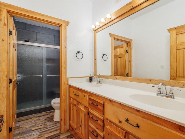 full bathroom featuring a sink, toilet, wood finished floors, and a shower stall