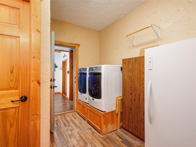 laundry room with washer and clothes dryer, a textured ceiling, wood finished floors, laundry area, and a textured wall