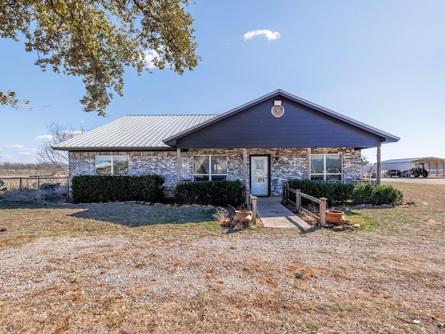 ranch-style home featuring brick siding, metal roof, and fence