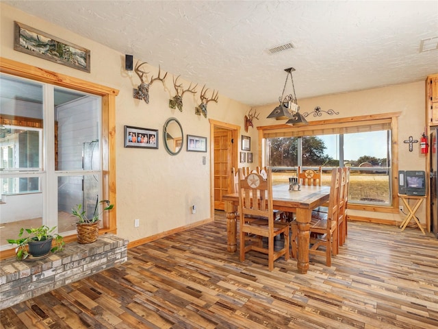 dining room with visible vents, baseboards, a textured ceiling, and wood finished floors