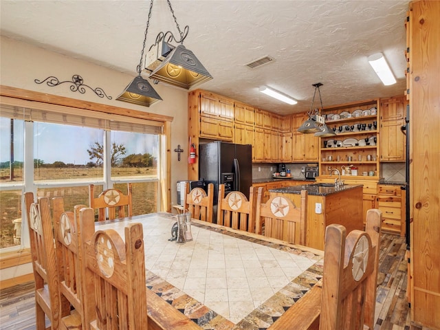 dining area with light wood-type flooring, visible vents, and a textured ceiling