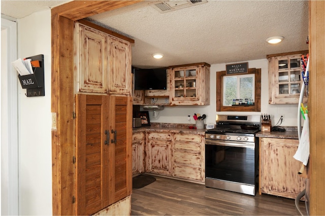 1719 E Bankhead Dr, Weatherford, TX 76086 - kitchen with gas stove, a textured ceiling, dark wood-style floors, dark countertops, and glass insert cabinets