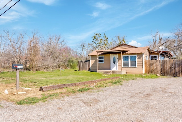 bungalow featuring a front lawn, fence, and driveway