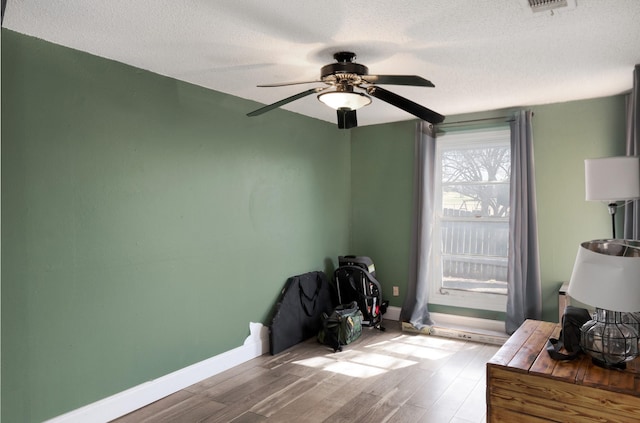 1719 E Bankhead Dr, Weatherford, TX 76086 - bedroom with baseboards, wood finished floors, a textured ceiling, and ceiling fan