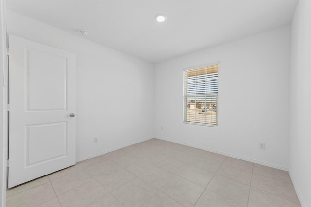 unfurnished room with light tile patterned floors and baseboards