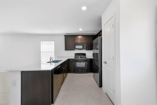 kitchen with light tile patterned floors, a sink, black appliances, light countertops, and dark brown cabinets