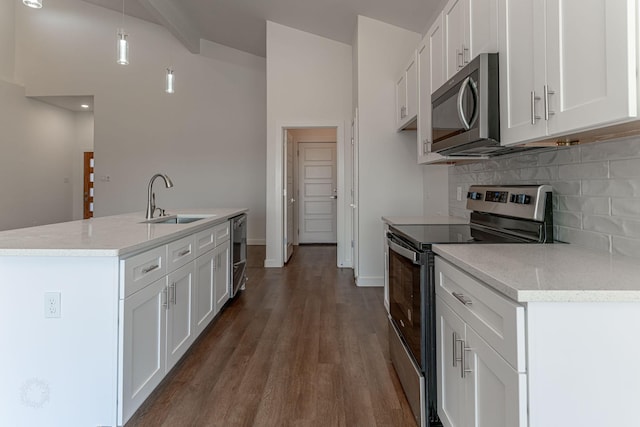 kitchen with a sink, backsplash, wood finished floors, white cabinetry, and stainless steel appliances