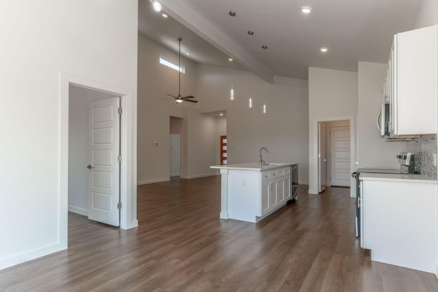 kitchen with a center island with sink, a sink, open floor plan, appliances with stainless steel finishes, and white cabinets