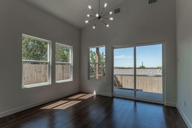 empty room featuring a chandelier, visible vents, baseboards, and wood finished floors