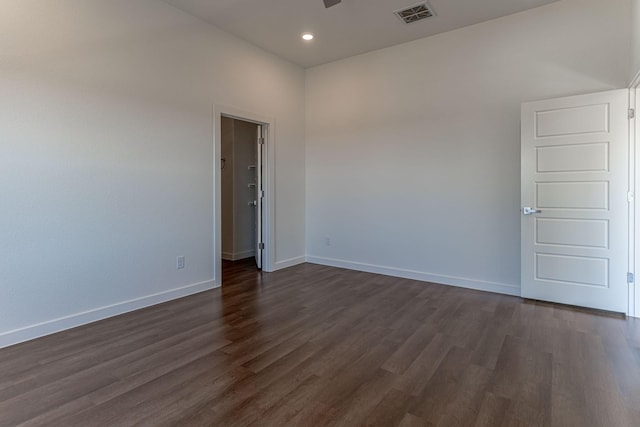 empty room featuring dark wood finished floors, visible vents, and baseboards