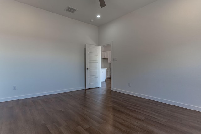 empty room featuring baseboards, visible vents, dark wood finished floors, ceiling fan, and a towering ceiling