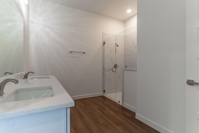 bathroom featuring a marble finish shower, wood finished floors, baseboards, and a sink