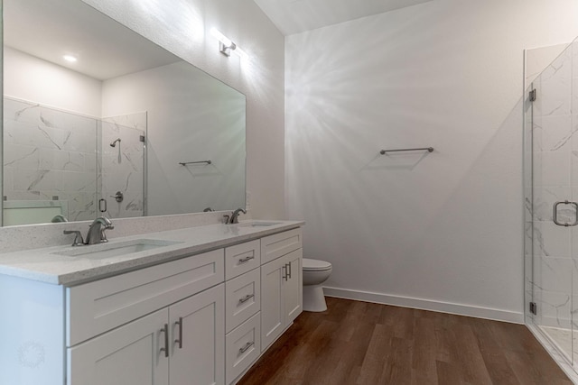 bathroom featuring a marble finish shower, wood finished floors, baseboards, and a sink