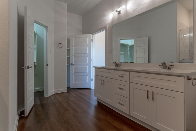 full bathroom with double vanity, wood finished floors, baseboards, and a sink