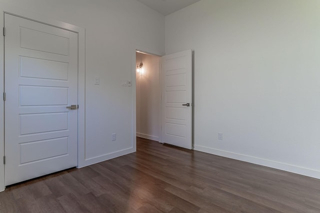 unfurnished bedroom with dark wood-type flooring and baseboards