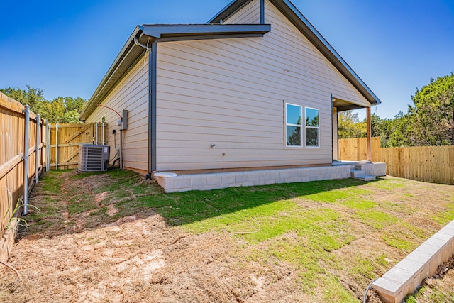 view of home's exterior with a lawn, central AC unit, and a fenced backyard