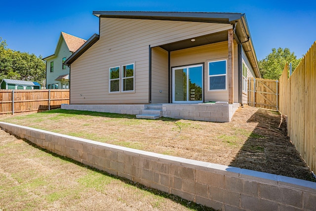 rear view of property featuring a lawn and a fenced backyard