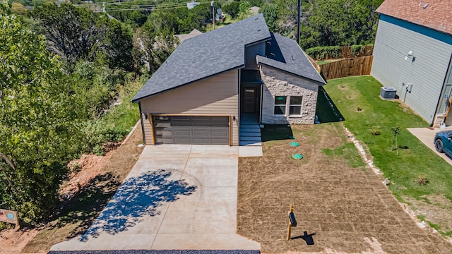 view of front of property with central AC unit, driveway, a shingled roof, a front lawn, and stone siding