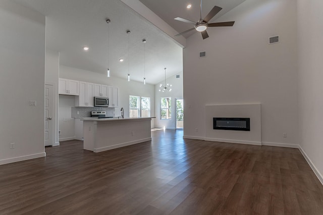 unfurnished living room with visible vents, a glass covered fireplace, dark wood finished floors, and ceiling fan with notable chandelier