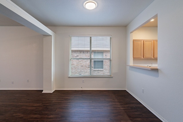 spare room with baseboards and dark wood finished floors