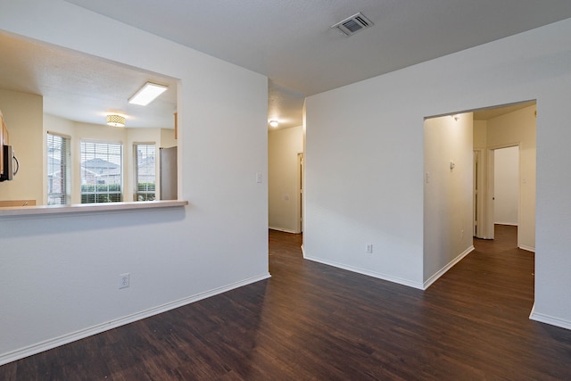 spare room featuring visible vents, baseboards, and wood finished floors