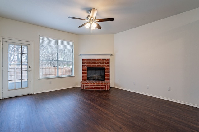 unfurnished living room featuring dark wood finished floors, a brick fireplace, baseboards, and ceiling fan