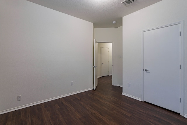 unfurnished bedroom with baseboards, visible vents, dark wood-style flooring, and a textured ceiling