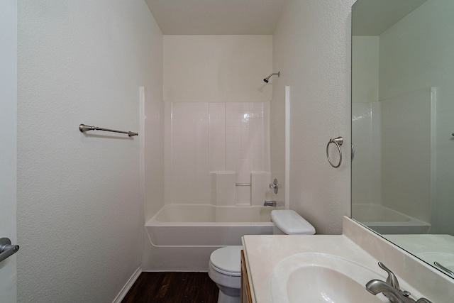 bathroom with vanity, wood finished floors, shower / tub combination, toilet, and a textured wall