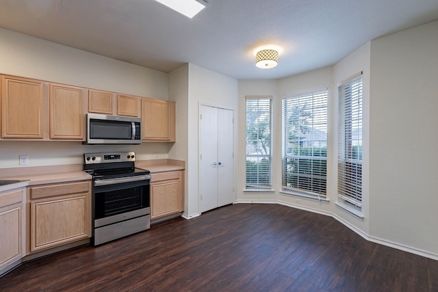 kitchen featuring light countertops, dark wood-style flooring, light brown cabinetry, and stainless steel appliances