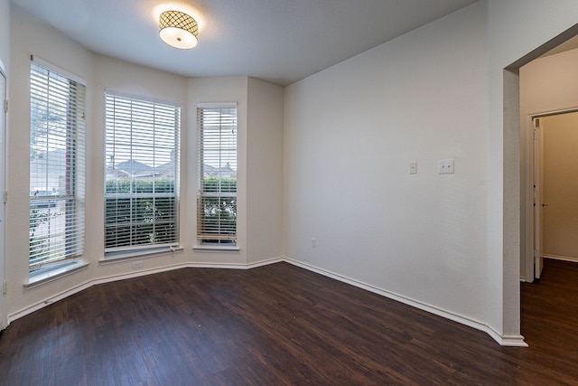 unfurnished room with baseboards and dark wood-type flooring