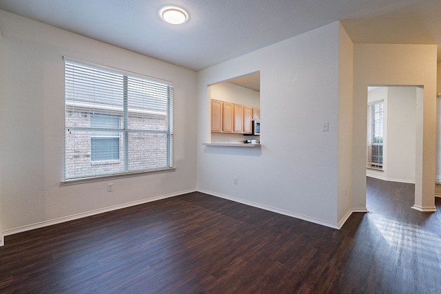 empty room featuring dark wood finished floors and baseboards