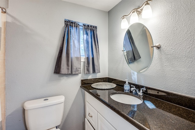 bathroom featuring vanity, toilet, and a textured wall