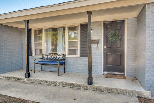 entrance to property featuring brick siding and covered porch