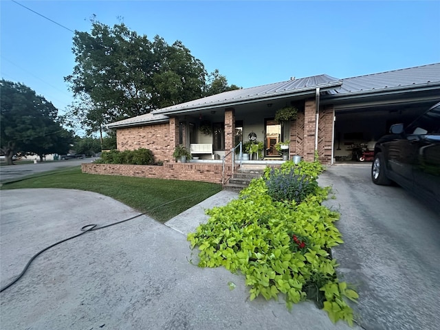 view of home's exterior with brick siding, driveway, metal roof, and a garage