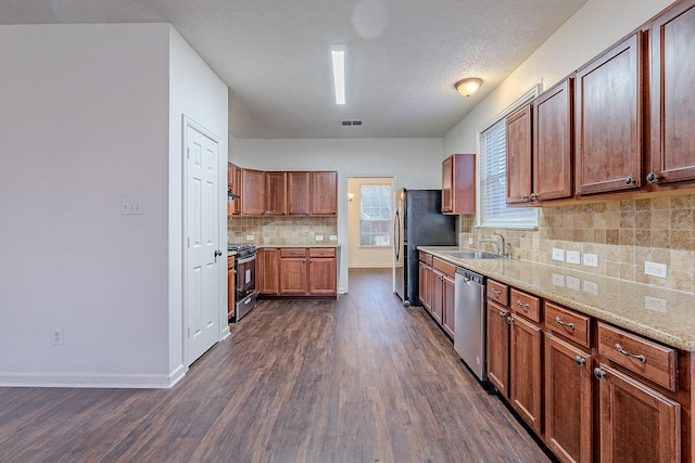 kitchen featuring a sink, stainless steel dishwasher, dark wood-style floors, freestanding refrigerator, and gas stove