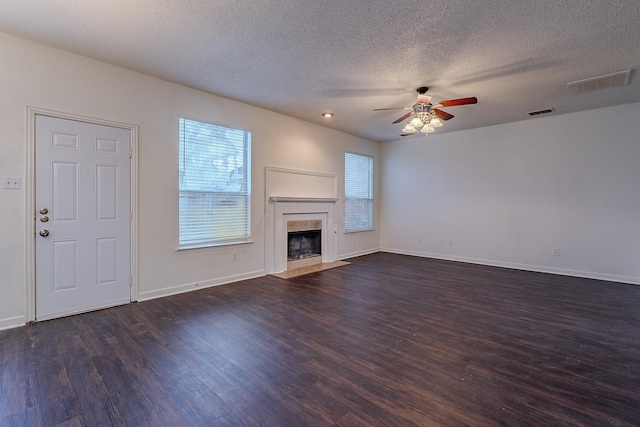 unfurnished living room with visible vents, a tile fireplace, dark wood-type flooring, and ceiling fan