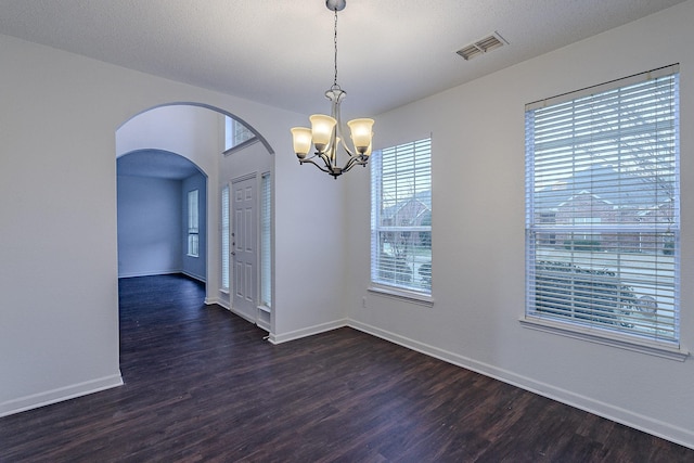 unfurnished room featuring visible vents, arched walkways, baseboards, and dark wood-style flooring