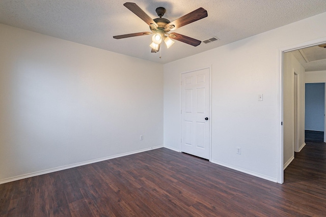 spare room featuring visible vents, baseboards, attic access, and dark wood finished floors