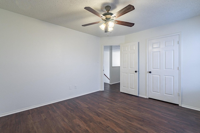 unfurnished bedroom with baseboards, a textured ceiling, and dark wood-style floors