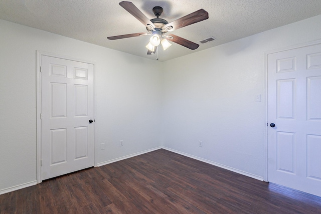 spare room featuring visible vents, dark wood-type flooring, baseboards, a textured ceiling, and a ceiling fan