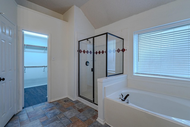 full bath featuring a textured ceiling, a stall shower, a spacious closet, stone finish flooring, and a garden tub