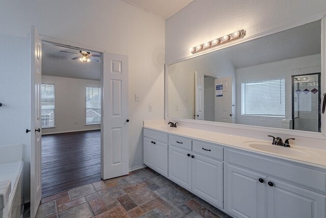 bathroom with double vanity, stone finish floor, lofted ceiling, and a sink