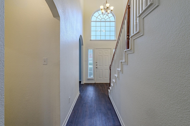 foyer featuring baseboards, plenty of natural light, wood finished floors, and a textured wall