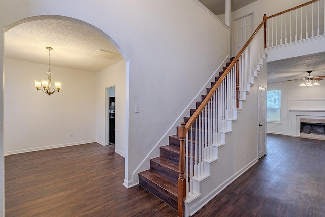 stairs with a textured ceiling, wood finished floors, and a fireplace