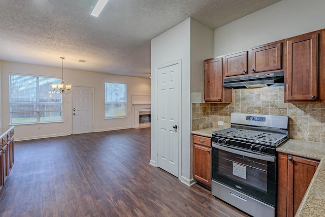 kitchen with stainless steel gas range oven, a notable chandelier, under cabinet range hood, dark wood-style floors, and a fireplace