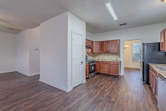 kitchen featuring visible vents, dark wood-type flooring, under cabinet range hood, appliances with stainless steel finishes, and light countertops