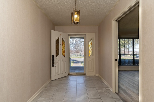 foyer entrance with baseboards, a textured ceiling, and crown molding